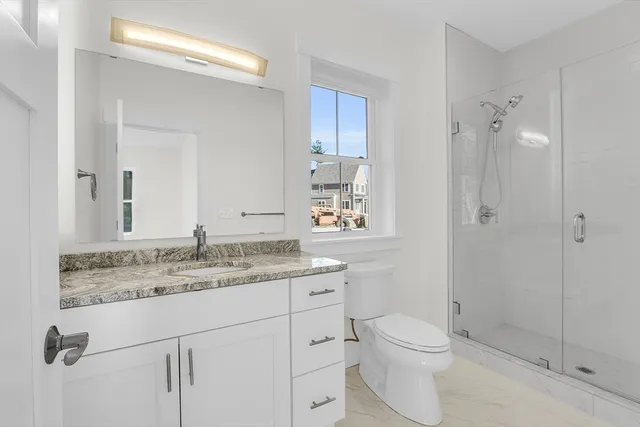 a bathroom with a granite countertop sink a toilet and shower