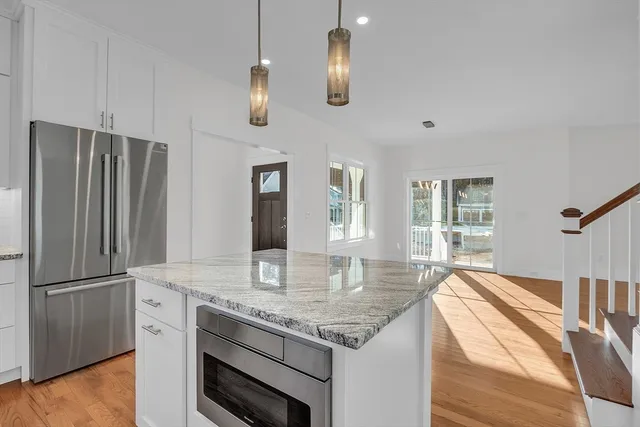 a kitchen with stainless steel appliances granite countertop a refrigerator a stove and a sink with wooden floor