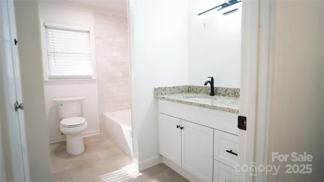 a bathroom with a granite countertop toilet and a sink