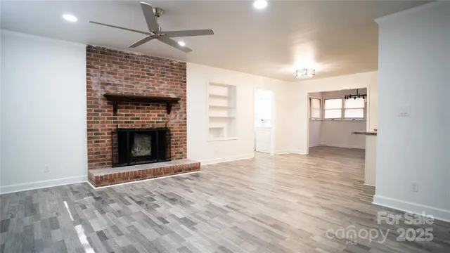 an empty room with wooden floor fireplace and windows