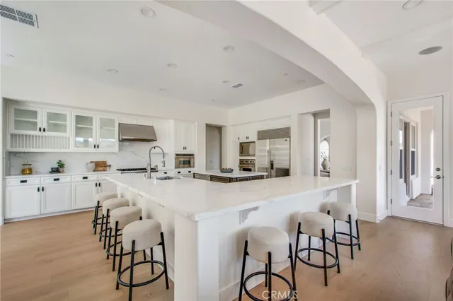 a kitchen with stainless steel appliances a sink a stove a refrigerator cabinets and dining table