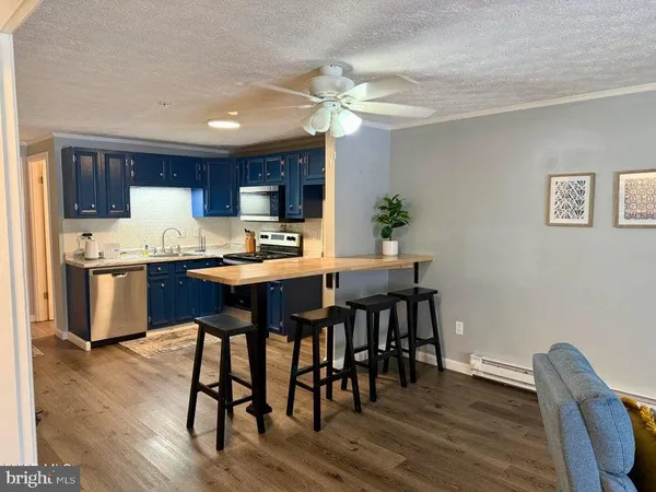 a kitchen with granite countertop wooden floors and view of living room