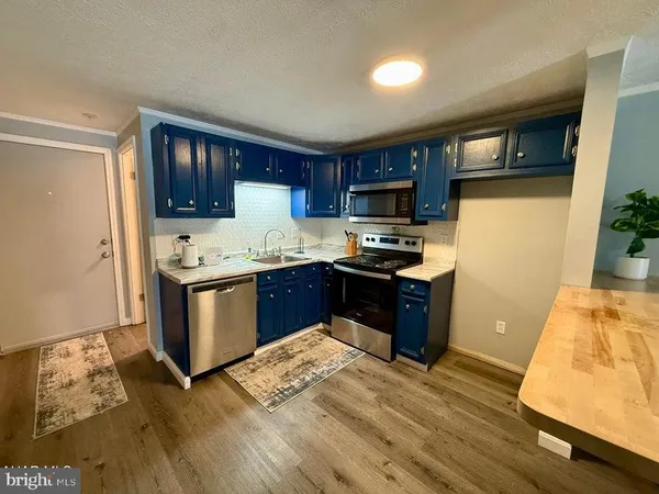 a kitchen with stainless steel appliances granite countertop a stove top oven a sink dishwasher and a refrigerator with wooden floor