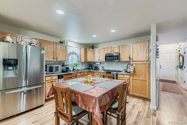 a kitchen with stainless steel appliances granite countertop a refrigerator a stove top oven a sink dishwasher and white cabinets with wooden floor