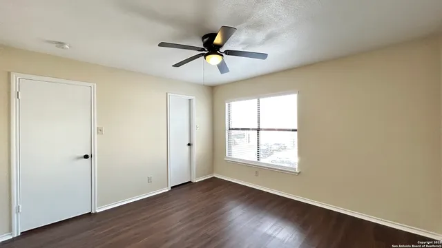 a view of a room with wooden floor and a ceiling fan