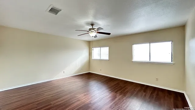 an empty room with wooden floor and windows
