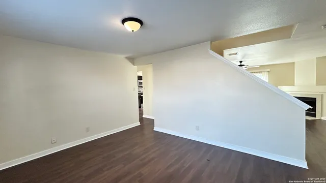 a view of an empty room with wooden floor and a fireplace
