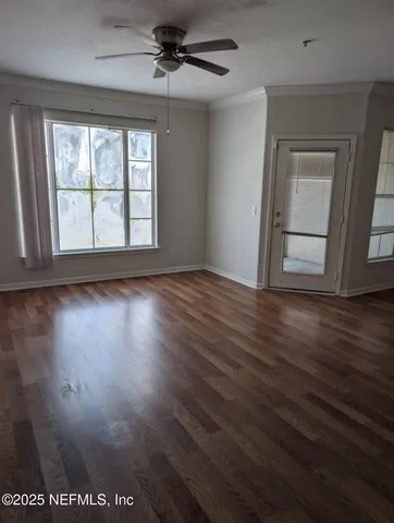 a view of an empty room with wooden floor and a window