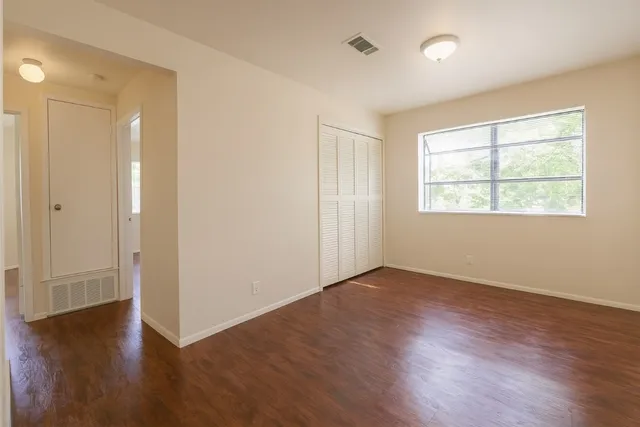 an empty room with wooden floor and windows
