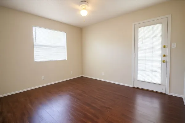 an empty room with wooden floor and windows