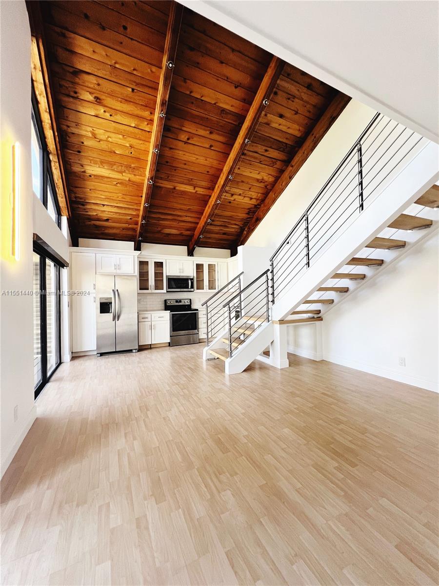 a view of an empty room with wooden floors and stairs