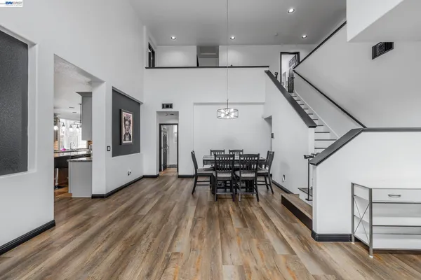 a dining room with wooden floor a chandelier a wooden table and chairs