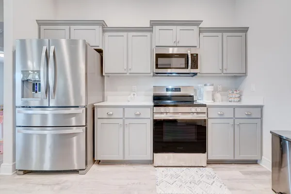 a kitchen with stainless steel appliances white cabinets white stove a microwave and a refrigerator