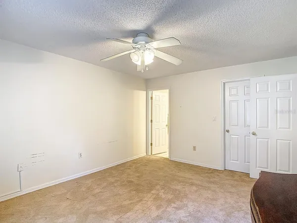 an empty room with a chandelier fan and windows