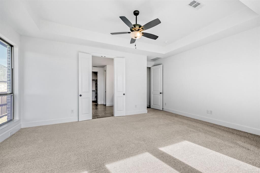 147 Derrett Lane Rhome, TX 76078 - Photo 13 of 28 Unfurnished bedroom with a tray ceiling, carpet floors, and a ceiling fan