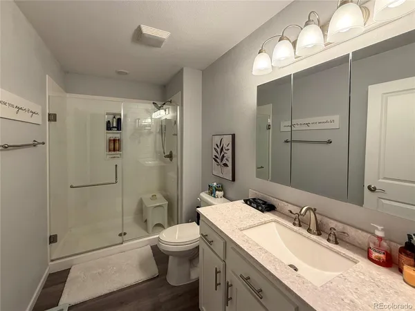 a bathroom with a granite countertop sink toilet and shower