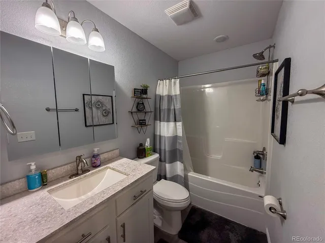 a bathroom with a granite countertop sink toilet and shower