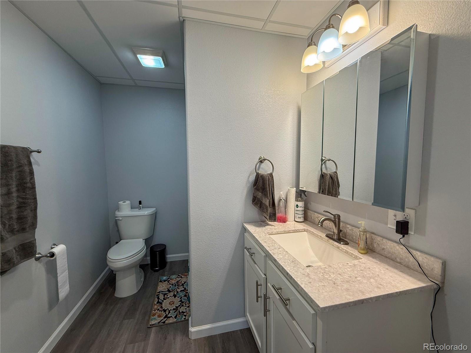 370 West 8th Street North, Unit A & B Cheyenne Wells, CO 80810 - Photo 42 of 47 a bathroom with a granite countertop sink a toilet and a mirror