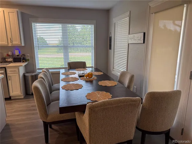a dining room with furniture a large window and wooden floor