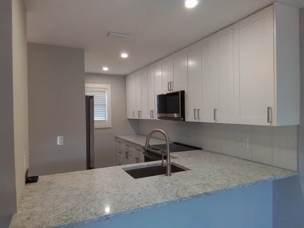 a kitchen with granite countertop white cabinets and stainless steel appliances