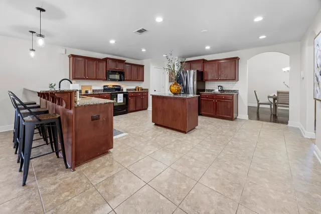 a kitchen with stainless steel appliances granite countertop a sink a stove and a wooden cabinets