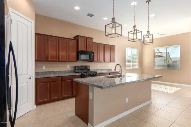 a kitchen with kitchen island granite countertop a sink cabinets a window and stainless steel appliances