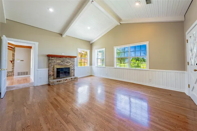 an empty room with wooden floor a fireplace and windows