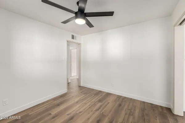 an empty room with wooden floor and ceiling fan