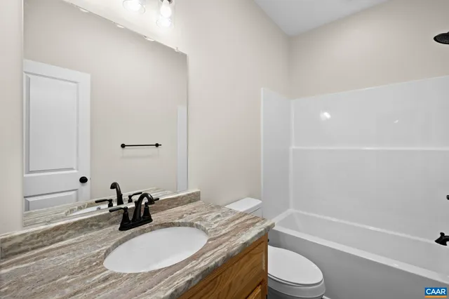a bathroom with a granite countertop sink toilet a mirror and shower