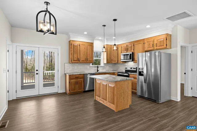 a large kitchen with stainless steel appliances granite countertop a stove a refrigerator a sink and a dishwasher with wooden floor