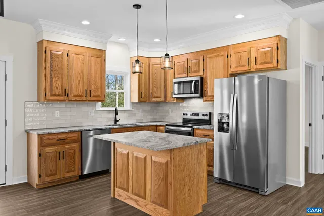 a kitchen with stainless steel appliances granite countertop a refrigerator a stove top oven a sink and dishwasher with wooden floor