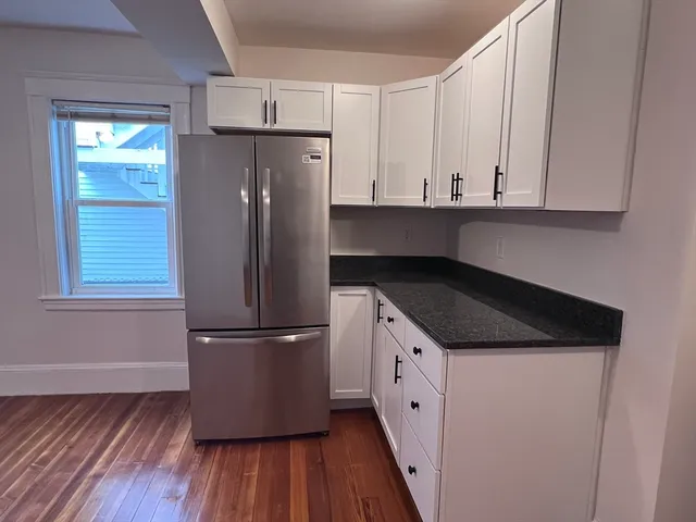 a kitchen with granite countertop a refrigerator sink and cabinets