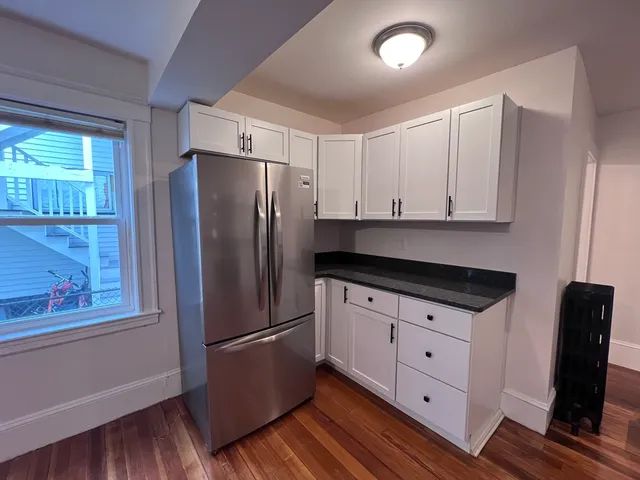 a kitchen with granite countertop white cabinets and refrigerator