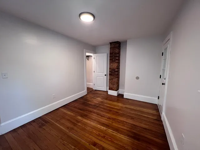 a view of an empty room with wooden floor and closet