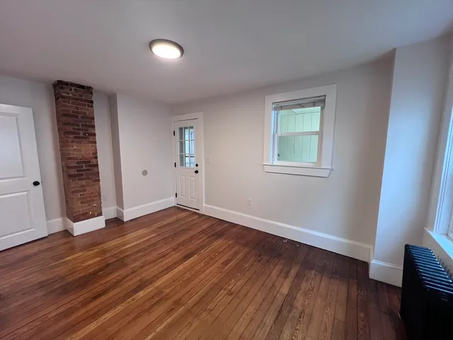 an empty room with wooden floor closet and windows