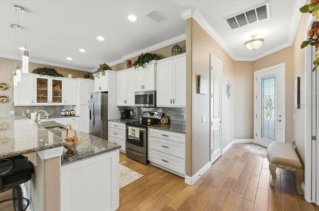 a kitchen with stainless steel appliances a microwave a stove a sink dishwasher and a refrigerator with wooden floor