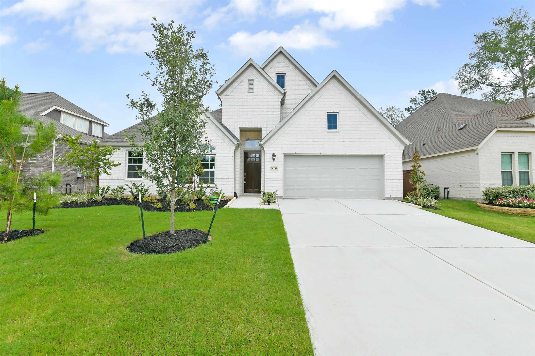 16119 Rustling Wds Road Conroe, TX 77302 - Photo 1 of 43 a view of a white house next to a yard with big trees