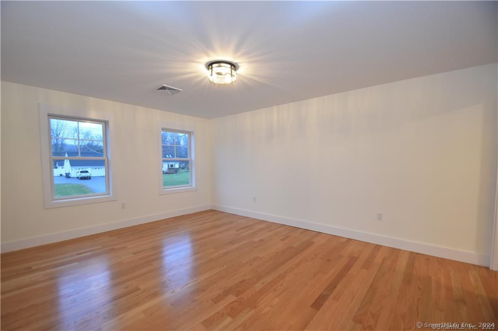 Mile Hill Road Tolland, CT 06084 - Photo 19 of 32 an empty room with wooden floor chandelier fan and windows
