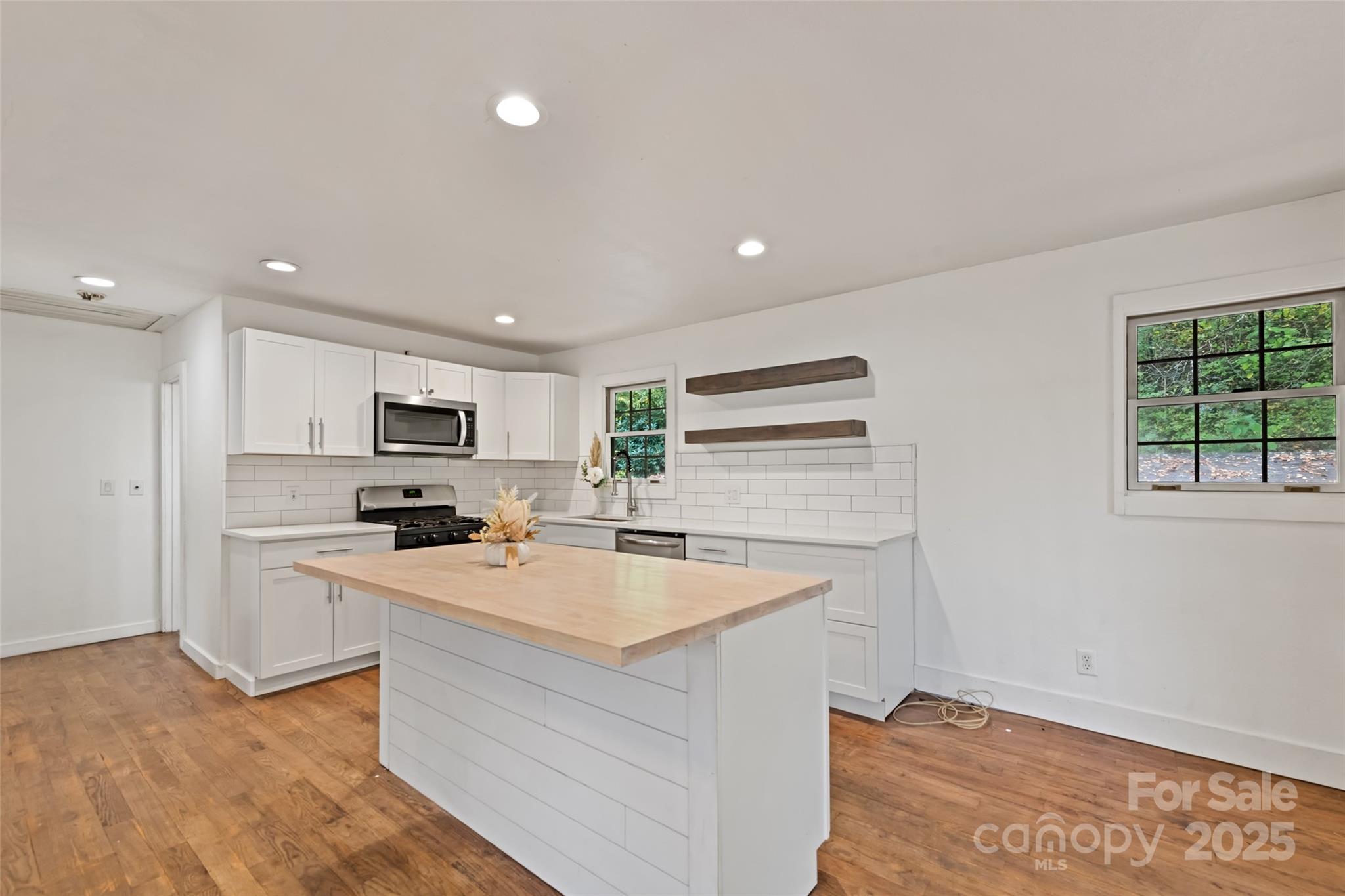 940 Haynes Cove Clyde, NC 28721 - Photo 19 of 48 a kitchen with stainless steel appliances a stove top oven a sink a refrigerator and white cabinets