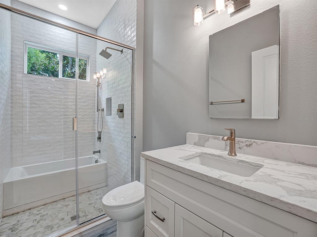 108 Irwin Street East Safety Harbor, FL 34695 - Photo 62 of 79 a bathroom with a granite countertop sink a toilet and shower