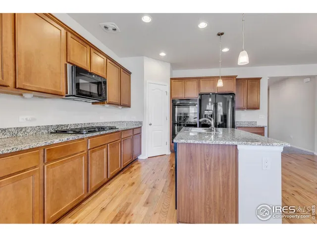a kitchen with stainless steel appliances granite countertop a sink a stove top oven a counter space and cabinets