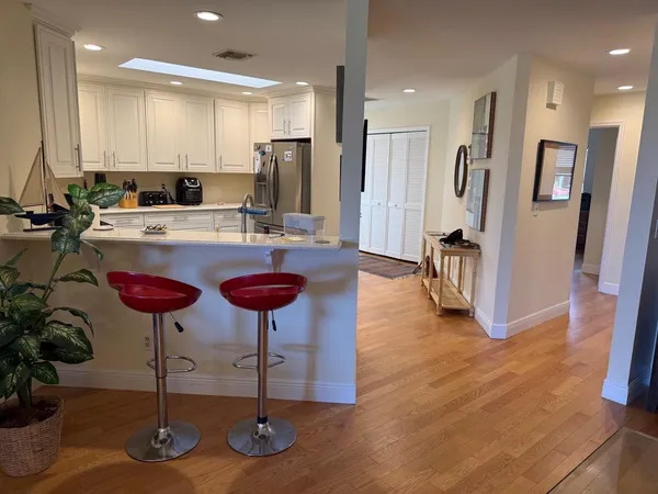 a kitchen with stainless steel appliances granite countertop a stove a refrigerator a sink a chair and white cabinets