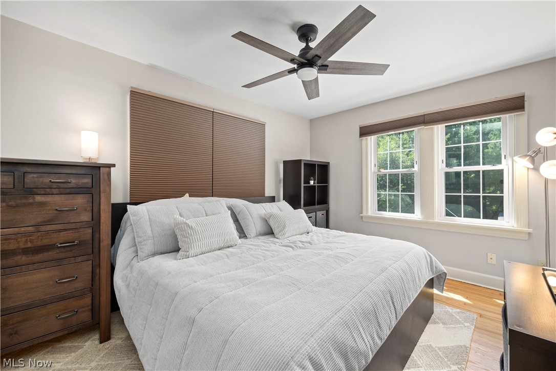 26019 Lake Road Bay Village, OH 44140 - Photo 20 of 40 Bedroom featuring light wood-finish flooring, a ceiling fan with integrated lighting, and multiple windows with white grid patterns