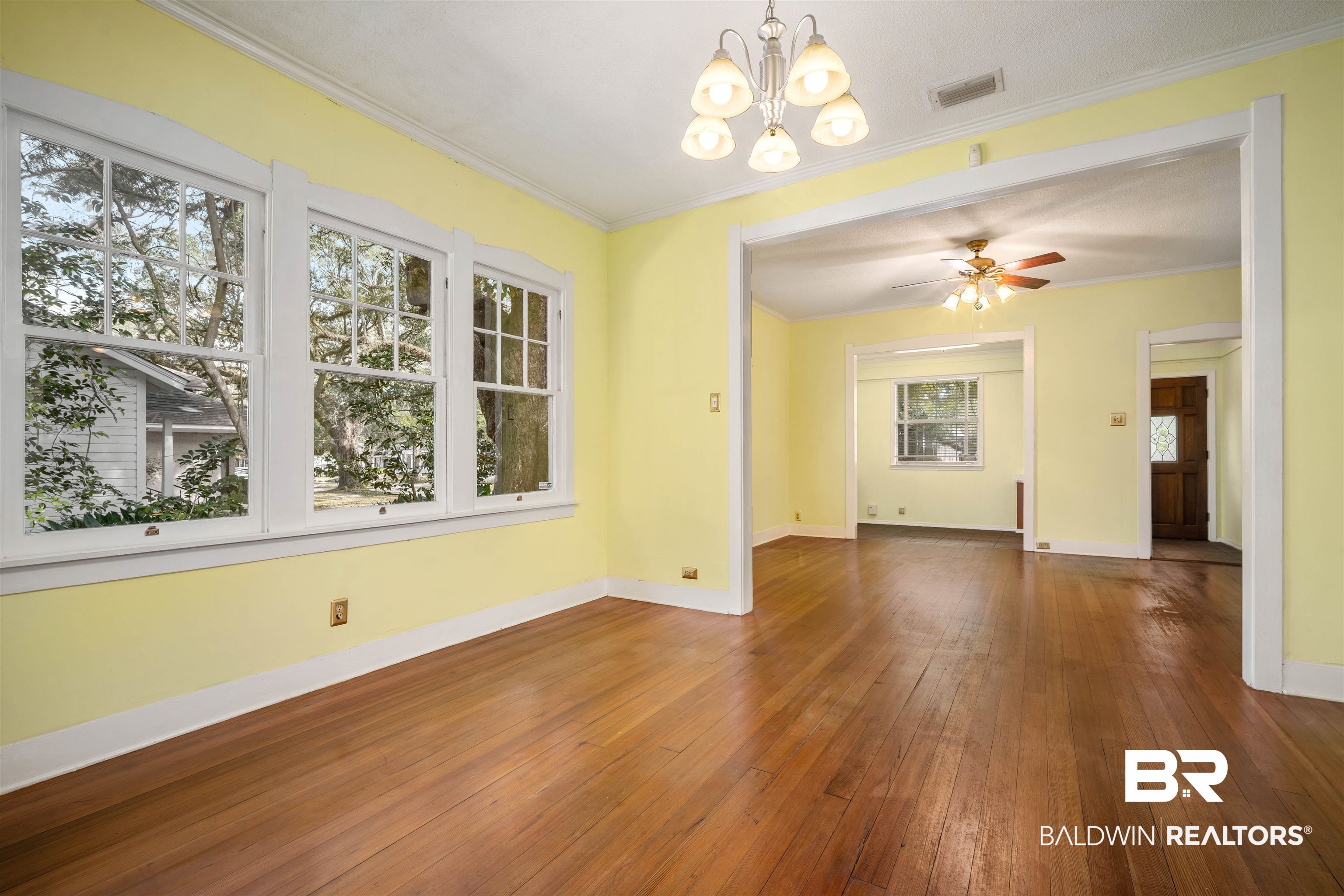 118 Mohawk Street Mobile, AL 36606 - Photo 9 of 26 Spare room featuring dark wood-type flooring, a chandelier, crown molding, and a ceiling fan