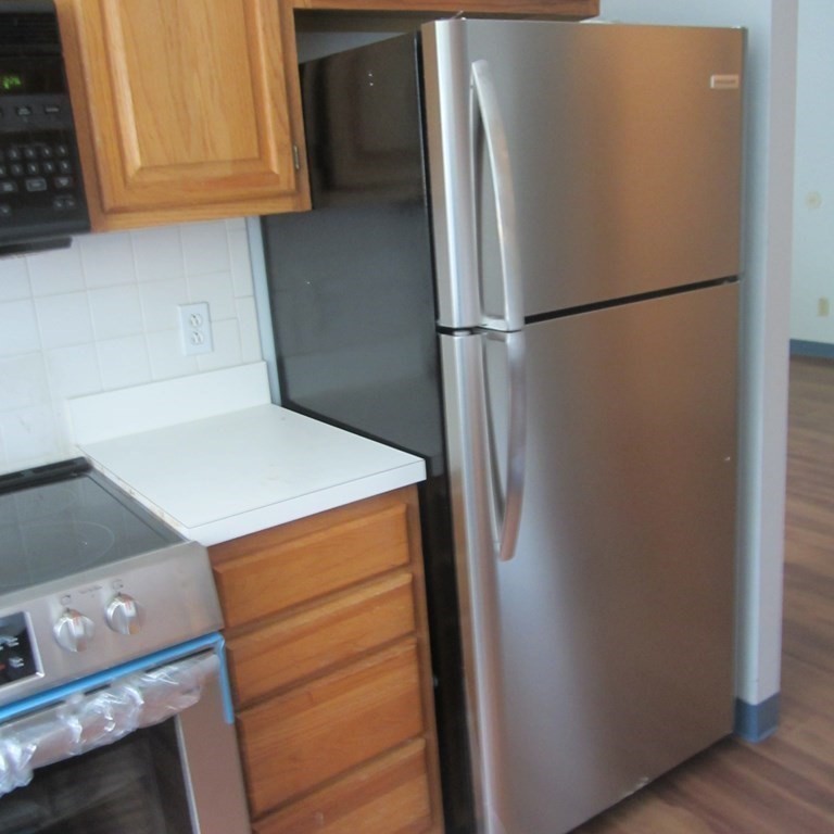 120 Fellsview Road, Unit 124 Stoneham, MA 02180 - Photo 13 of 20 a view of a refrigerator in kitchen and an empty room with wooden floor
