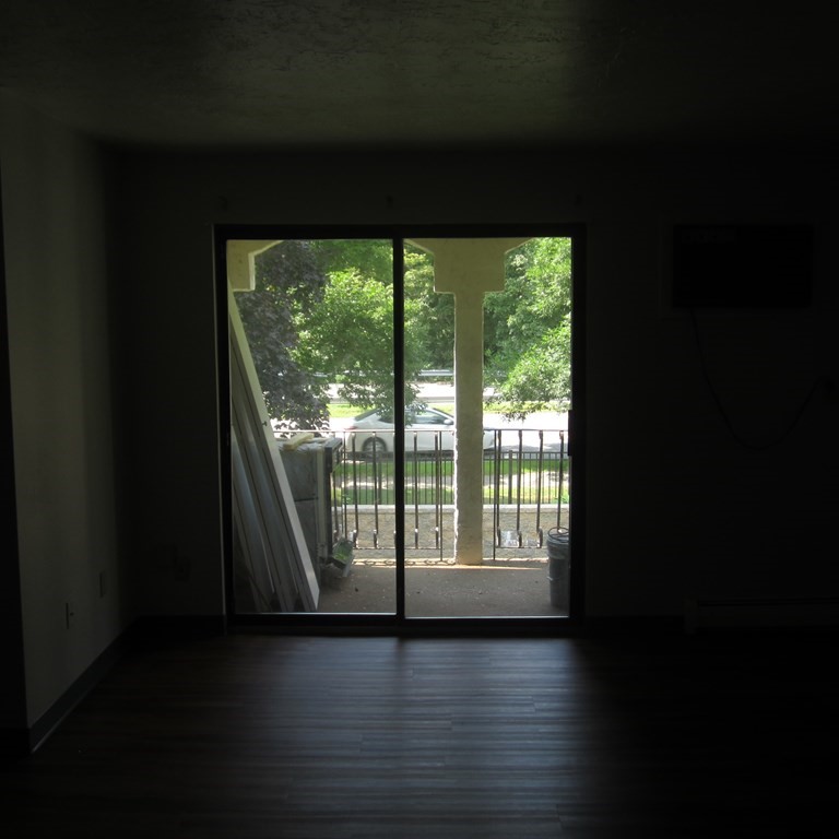 120 Fellsview Road, Unit 124 Stoneham, MA 02180 - Photo 4 of 20 a view of an empty room with wooden floor and a window