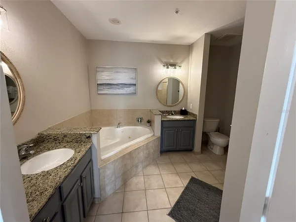 a bathroom with a granite countertop sink a toilet a mirror and vanity