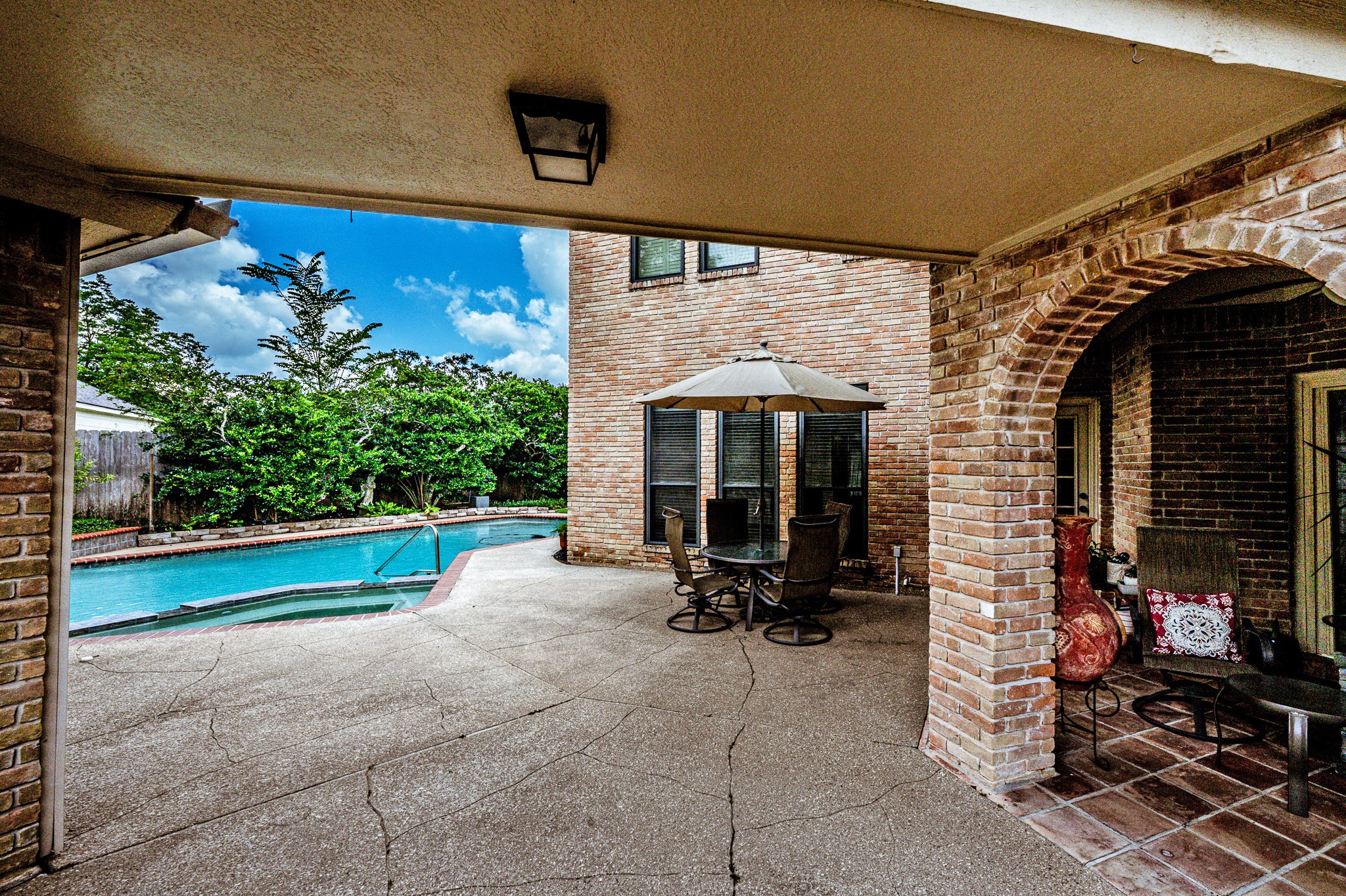 6047 Spring Creek Lane Spring, TX 77379 - Photo 37 of 50 Inside the backyard, the covered patio extends the home’s living spaces with a setting designed for relaxed afternoons and easy outdoor entertaining. Brick archways, pool views, and generous shaded seating give the space a timeless resort style atmosphere.