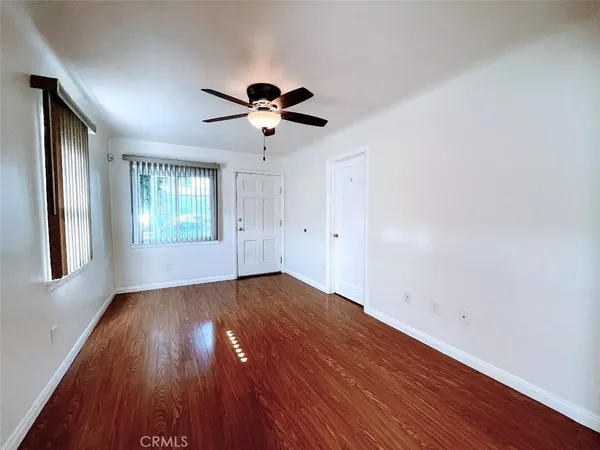 an empty room with wooden floor chandelier fan and windows