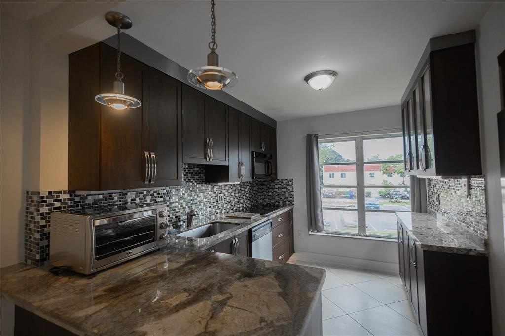 4152 Inverrary Drive, Unit 202 Lauderhill, FL 33319 - Photo 6 of 13 a kitchen with stainless steel appliances kitchen island granite countertop a stove a sink and a microwave